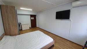 a bedroom with a bed and a flat screen tv at Goodzone Hostel in Volgograd