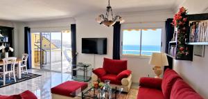 プエルト・デ・サンティアゴにあるVitacrab Penthouse in erster Meereslinieの赤い家具付きのリビングルームが備わり、海の景色を望めます。