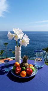 einen Tisch mit einem Obstteller und einer Vase mit Blumen in der Unterkunft Vitacrab Penthouse in erster Meereslinie in Puerto de Santiago