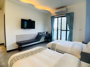Una habitación de hotel con dos camas y un televisor de pantalla plana. en 旭語民宿 台東縣民宿1436號, en Chishang