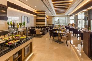 a restaurant with tables and chairs and a buffet at Golden Tulip Media Hotel in Dubai
