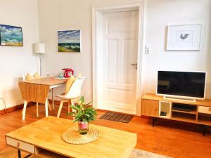 a living room with a television and a table at Ferienwohnung Schönwälder mit kleiner Terrasse und WALL BOX in Buxtehude
