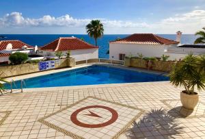 a swimming pool in front of a house with the ocean at Vitacrab Penthouse in erster Meereslinie in Puerto de Santiago