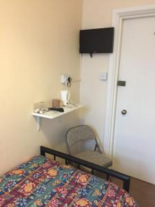 um quarto com uma cama, uma cadeira e uma porta em Longfield Guest House em Dover