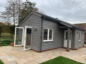 a grey shed with two windows and a patio at The Boat House in Chichester