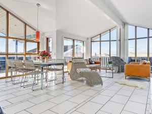 a living room with a table and chairs and windows at 8 person holiday home in Hj rring in Hjørring