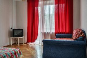 a room with red curtains and a chair and a television at Alexandrovskaya street in Zaporozhye