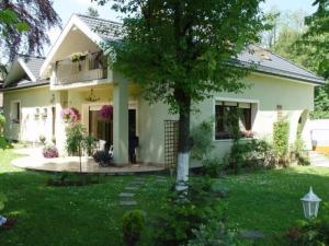 una pequeña casa blanca con un árbol en el patio en DOMEK Zielona Oaza, en Polanica-Zdrój