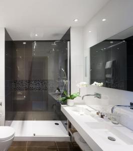 La salle de bains est pourvue de 2 lavabos, d'une douche et de toilettes. dans l'établissement Isola di Albarella Golf Hotel, à Albarella