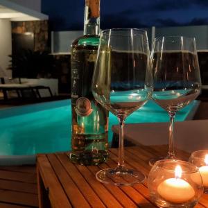 two wine glasses on a table next to a bottle of wine at Villa Shepherd Lajares - LUXURY VILLA FUERTEVENTURA in Lajares