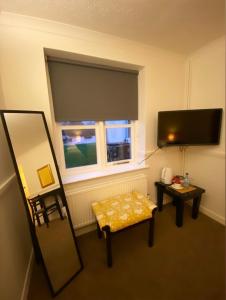 a room with a mirror and a television and a chair at Old Rectory Country Hotel in Crickhowell