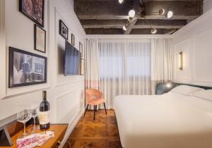 um quarto com uma cama branca e uma mesa com copos de vinho em Brown BoBo, a member of Brown Hotels em Tel Aviv