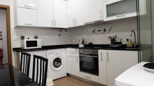 a kitchen with white cabinets and a washer and dryer at Oliveira's Dream - Stay Good, Feel Good in Maia