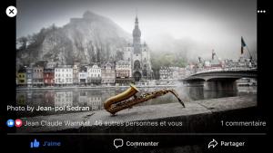 a picture of a saxophone sitting on a ledge next to a bridge at Les Voisins De Mr Sax in Dinant