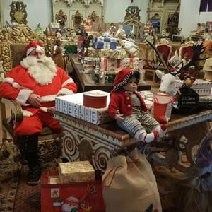 Eine Santa-Klausel und ein Kind, das an einem Tisch in einem Laden sitzt. in der Unterkunft Königreich Romkerhall in Schulenberg im Oberharz