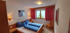 a bedroom with a blue bed and a window at Pension Appartements Via Claudia in Lermoos