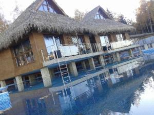 a large building with a thatched roof reflecting in the water at Бора Бора in Sapareva Banya