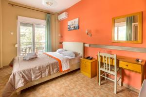 a bedroom with orange walls and a bed and a desk at Hotel Almira in Agia Triada