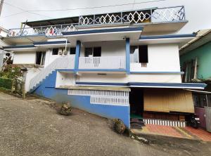 a white and blue building with a balcony at Gokulam Holiday Home in Munnar