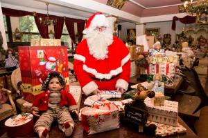 un Santa Claus de pie en una habitación llena de regalos en Königreich Romkerhall en Schulenberg im Oberharz