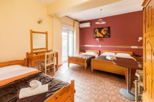 a bedroom with two beds and a table and a mirror at Hotel Almira in Agia Triada
