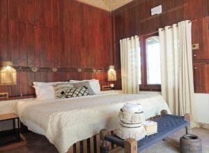 1 dormitorio con 1 cama grande y paredes de madera en Sunsets and Palm Trees, en Alleppey