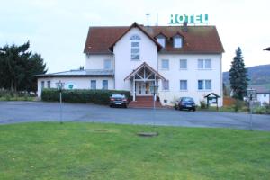 a large white building with cars parked in front of it at Hotel Linden in Knüllwald