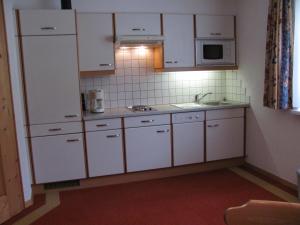 フリルシュにあるHaus Wechnerの白いキャビネット、シンク、電子レンジ付きのキッチンが備わります。
