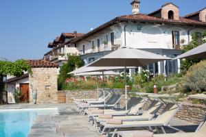 a row of lounge chairs with umbrellas next to a pool at Agriturismo La Torricella in Monforte dʼAlba