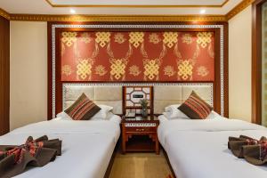 a room with two beds and a table between them at Floral Hotel · Shangri-la Blue Sky in Shangri-La