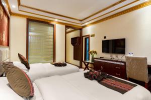 a hotel room with two beds and a flat screen tv at Floral Hotel · Shangri-la Blue Sky in Shangri-La