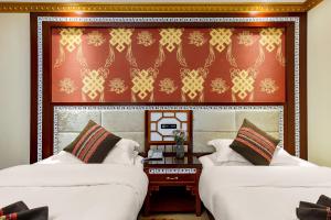 two beds in a room with a wall at Floral Hotel · Shangri-la Blue Sky in Shangri-La