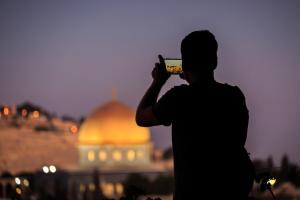 un homme qui prend une photo d'une mosquée avec son téléphone portable dans l'établissement Hashimi Hotel, à Jérusalem