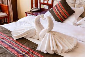 two swans made out of towels sitting on a bed at Floral Hotel · Shangri-la Blue Sky in Shangri-La