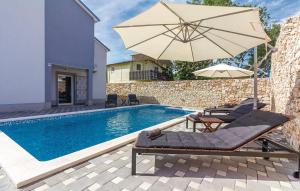 a swimming pool with an umbrella and chairs next to a swimming pool at Holiday Home Ivan in Peroj