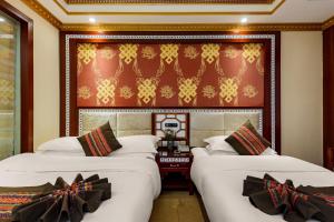two beds in a room with a headboard at Floral Hotel · Shangri-la Blue Sky in Shangri-La