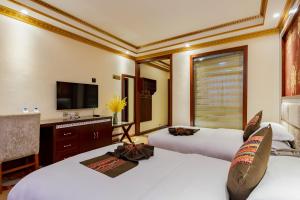 a hotel room with two beds and a television at Floral Hotel · Shangri-la Blue Sky in Shangri-La