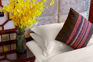 a vase of yellow flowers sitting on a table with pillows at Floral Hotel · Shangri-la Blue Sky in Shangri-La