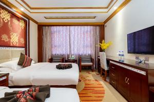 a hotel room with two beds and a flat screen tv at Floral Hotel · Shangri-la Blue Sky in Shangri-La