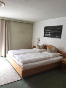 Un dormitorio con una gran cama de madera con sábanas blancas. en Haus Arnold Schranz, en Sankt Anton am Arlberg