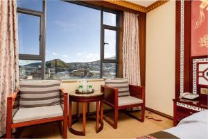 a room with two chairs and a table and a window at Floral Hotel · Shangri-la Blue Sky in Shangri-La