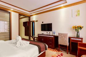 a hotel room with a bed and a desk and a television at Floral Hotel · Shangri-la Blue Sky in Shangri-La