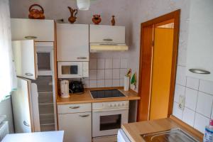 cocina pequeña con armarios blancos y fogones horno superior en Ferienhaus Weise, en Unterweißbach