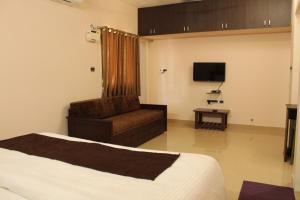 een slaapkamer met een bed, een stoel en een televisie bij Phoenix Serviced Apartment - Sri Illam in Chennai