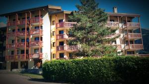 un gran edificio de apartamentos con un árbol delante en Les 3 marmottes- le Solaret, en Bourg-Saint-Maurice