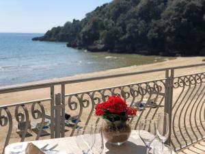 a table with wine glasses and a vase with red flowers at Grand Hotel Il Ninfeo in Gaeta