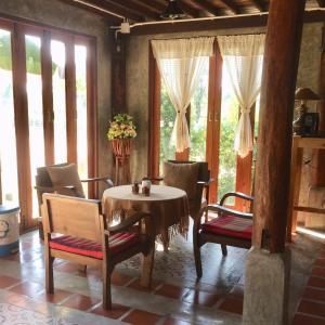 a dining room with a table and chairs and windows at เฮือนฮอมคำโฮมสเตย์(Huanhomkham homestay) in Chiang Mai