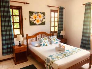 1 dormitorio con 1 cama y 2 ventanas en Sunset Cove Villa, en Grand'Anse Praslin