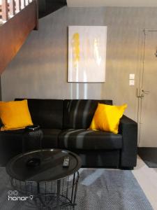 Appartement Le 146 Bis, avec Parking في رين: أريكة سوداء مع وسائد صفراء في غرفة المعيشة