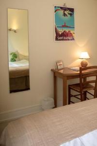 a bedroom with a bed and a desk with a mirror at Hôtel Du Soleil in Saint-Raphaël